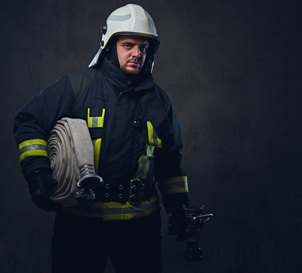 Retrato de un bombero sostiene manguera de fuego
 - Foto, imagen