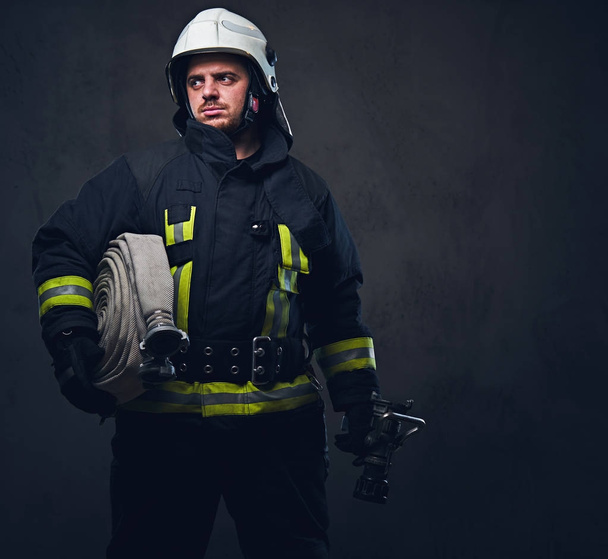 Portrait of a firefighter holds fire hose - Photo, Image