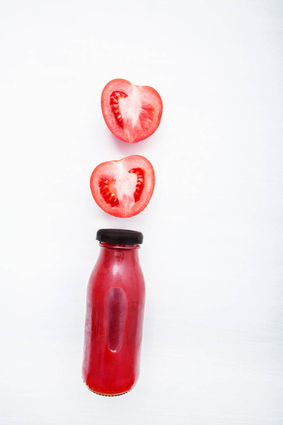 Tomatoes juice in bottle and fresh tomatoes slices on white wood - Foto, Imagem