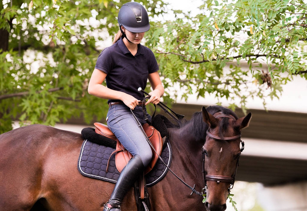Mooi meisje berijden van een paard met achtergrondverlichting achterlaat  - Foto, afbeelding