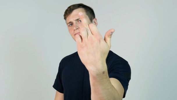 Young Man Showing Middle Finger Isolated on White. Young angry man with black t-shirt looking at camera and showing middle finger - Photo, Image