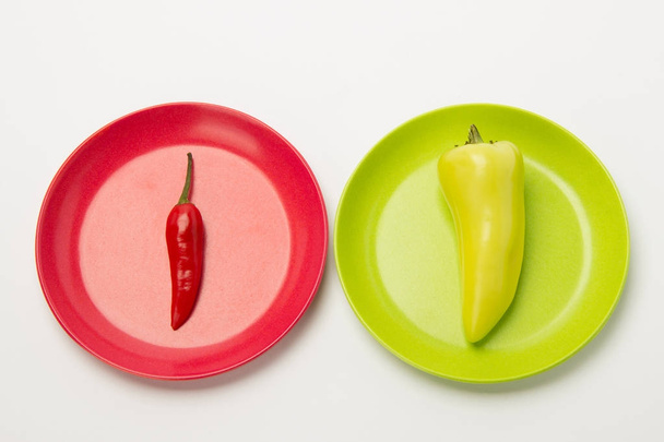 rote scharfe reife Paprika und grüne Süße auf einem flachen Teller auf einem weißen B - Foto, Bild