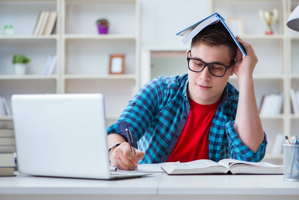Jeune adolescent se préparant pour les examens étudiant à un bureau à l'intérieur - Photo, image