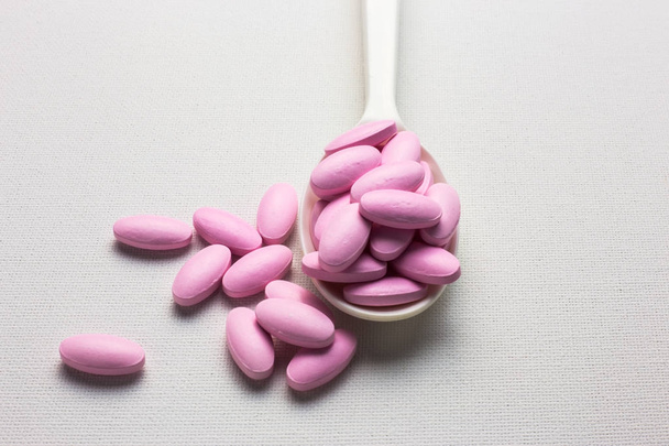 Muchas pastillas de color rosa en una cuchara
 - Foto, imagen