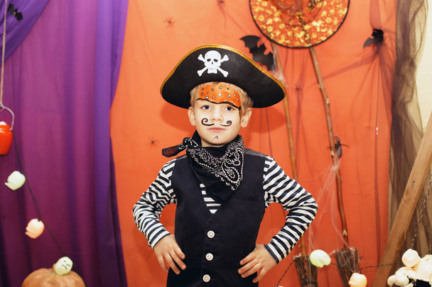 Вечірка на Хелловін. Маленький хлопчик у піратському костюмі та макіяжі на обличчі добре проводить час на вечірці на Хелловін. Обличчя малюють діти. Дитина серед прикрас Хеллоуїна
 - Фото, зображення