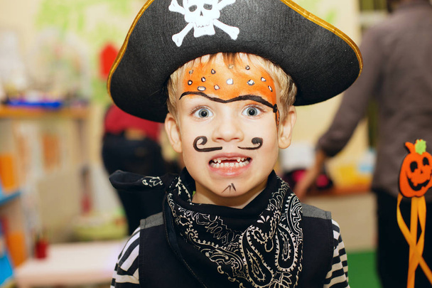 Halloween party. A little boy in a pirate costume and a makeup on his face is having a good time at the Halloween party. Face painting kids. Toothless mouth - Photo, Image