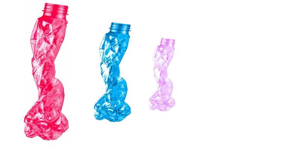 rote, blaue und rosa verdrehte Plastikflaschen sind so geformt wie drei Personen, die in einer Reihe auf weißem Hintergrund mit Kopierraum gehen - Foto, Bild