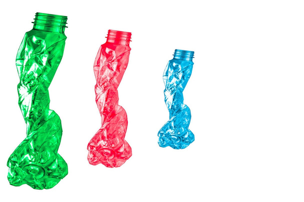 grüne, rote und blaue verdrehte Plastikflaschen haben die Form von fünf Personen, die in einer Reihe auf weißem Hintergrund mit Kopierraum gehen. - Foto, Bild