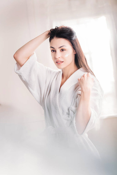 woman in bathrobe with cream on face - Foto, imagen