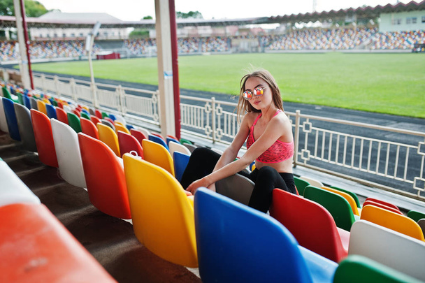 Fitness sporty girl in sportswear and sunglasses posed at stadiu - Fotoğraf, Görsel