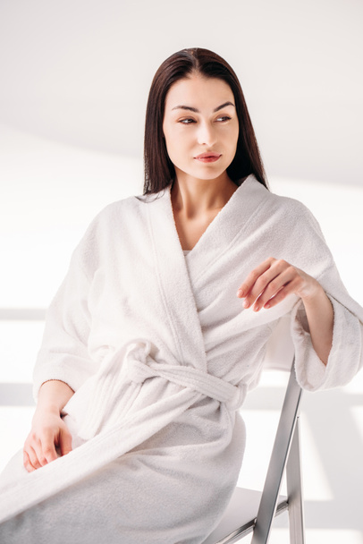young woman in bathrobe relaxing on chair - Foto, afbeelding