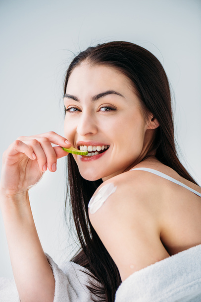 Smiling woman eating slice of cucumber - 写真・画像