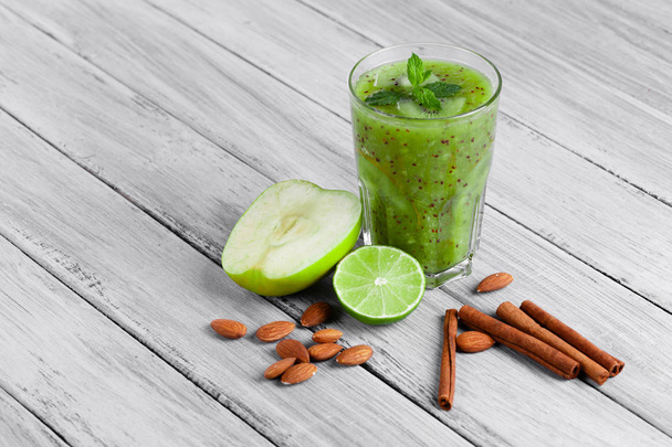 top view of glass of smoothie from kiwi, apple, and lime with mint on a gray wooden background. - Foto, imagen