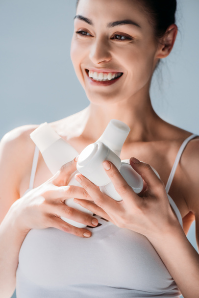 Mujer sonriente sosteniendo recipientes cosméticos
 - Foto, imagen