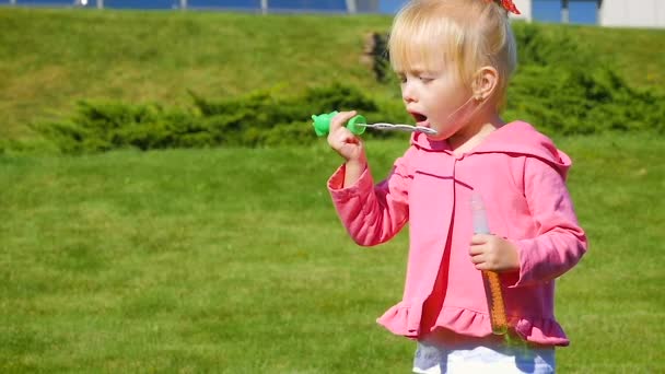 SLOW MOTION: pieni hauska tyttö kolmen vuoden puhaltaa saippuakupla kaupungin puistossa
. - Materiaali, video