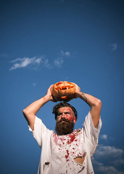 Hombre de Halloween sosteniendo la calabaza sobre el cielo azul
 - Foto, imagen