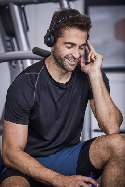 Smiling guy in gym with headphones - Photo, image