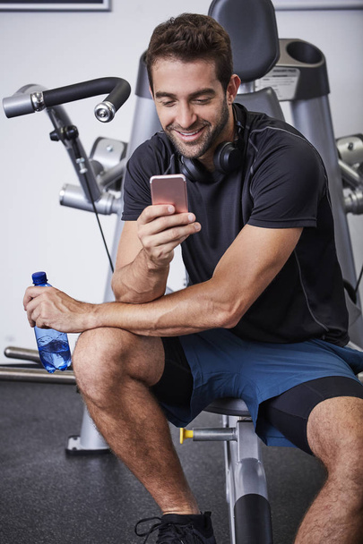Texting athlete taking a break in gym - Photo, image