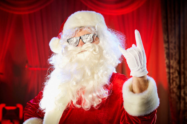 Santa Claus shows a hand a heavy rock symbol. - 写真・画像