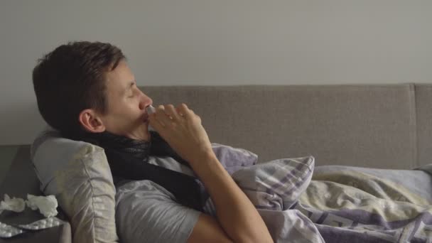 hombre acostado enfermo en la cama junto a sus medicamentos en su casa y espolvorea un aerosol nasal en su nariz
 - Metraje, vídeo