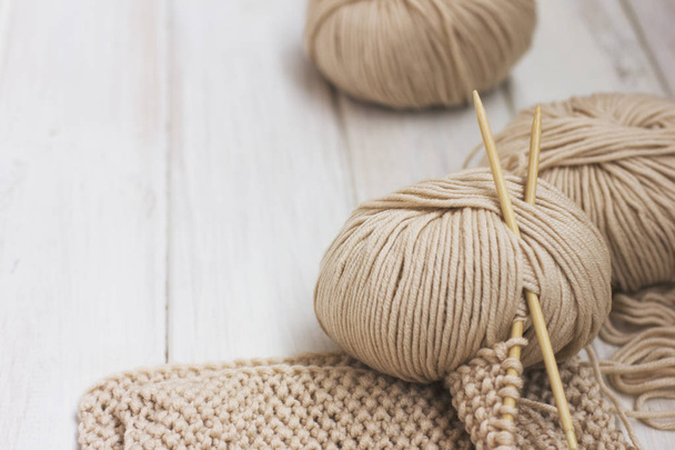 Beige Merino yarn with bamboo needles on white wooden background - Φωτογραφία, εικόνα