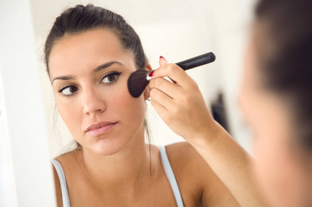 Beautiful young woman making make-up near mirror at home. - Foto, afbeelding