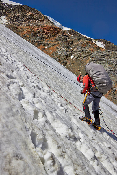 Alpinist climbing a mountain with snow field - 写真・画像