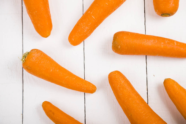 Ripe carrots on a white wooden table.   - 写真・画像