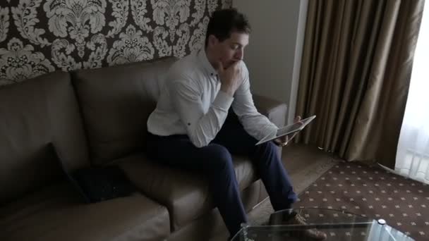 businessman in shirt sitting on sofa and using digital tablet at room - Video
