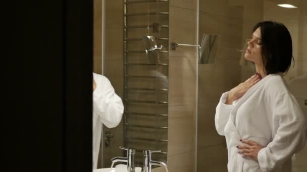 brunette woman in white robe refresh body with water in bathroom at home - Filmmaterial, Video