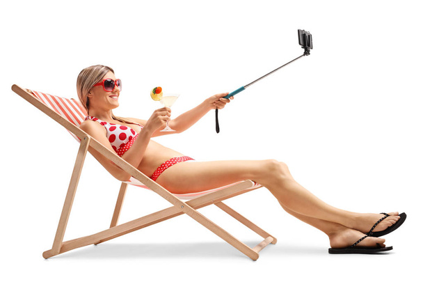 woman sitting in a deck chair and taking a selfie - Fotografie, Obrázek