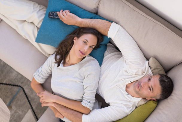 Young couple on the sofa watching television top view - Foto, imagen