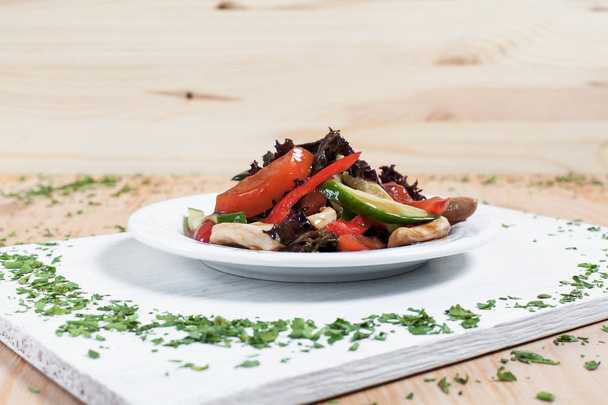salaatti syksyn vihanneksia kurkkua, pippuria, tomaattia, kaalia ja kanafileetä vihreillä valkoisella lautasella valkoisella pöydällä, puupohjalla
 - Valokuva, kuva