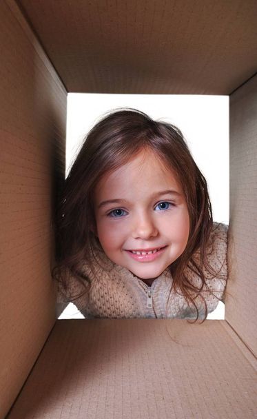 Cute little girl looking through paper box isolated on white background - Φωτογραφία, εικόνα