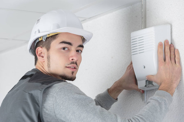 electrician fitting a thermostat system - Foto, Bild
