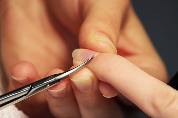 Uno studente ai corsi di formazione di una manicure prepara la mano di una cliente donna con una forbice manicure per cuticole prima di applicare la gommalacca.
. - Foto, immagini