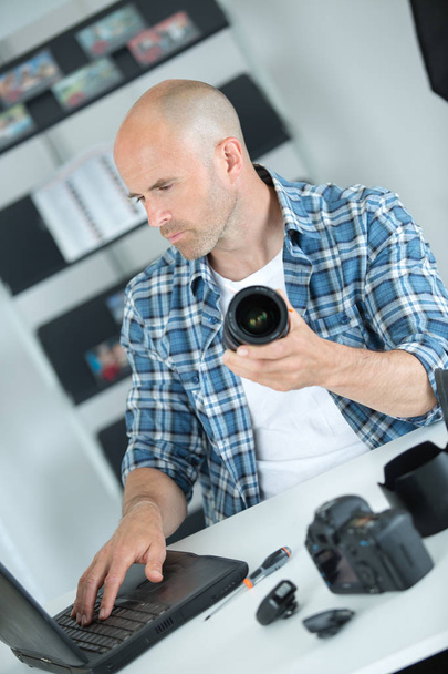 photographer checking how to clean camera online - Zdjęcie, obraz