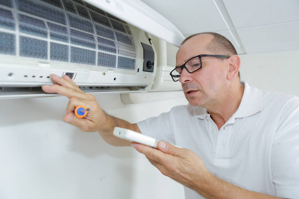 man adjusting air conditioning system - Foto, afbeelding