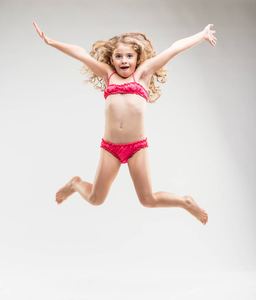 Хитрая, буйная маленькая девочка, прыгающая в воздухе
 - Фото, изображение