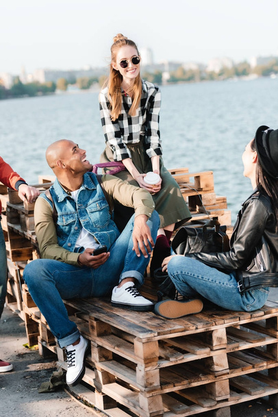 Multikulturelle Freunde ruhen sich auf Pier aus - Foto, Bild