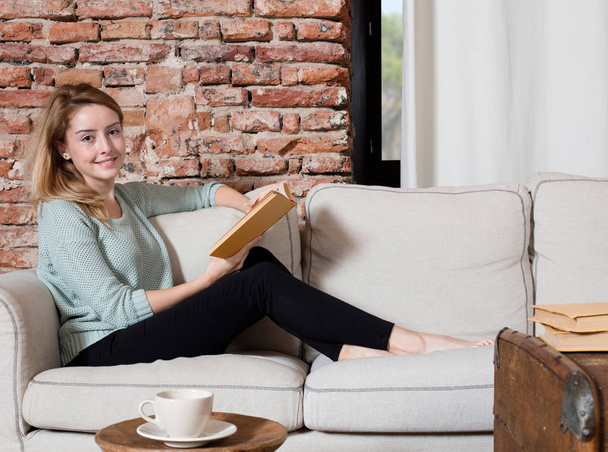 Girl with book on sofa - Φωτογραφία, εικόνα