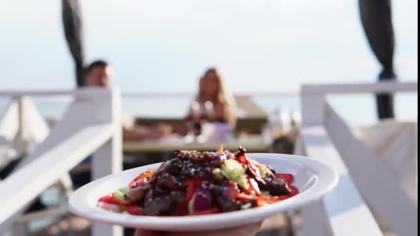 Le serveur porte une salade pour le couple qui dîne dans un restaurant près de l'eau
 - Séquence, vidéo
