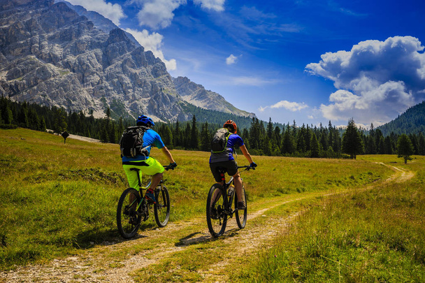 Mountain biking couple with bikes on track, Cortina d'Ampezzo, D - Photo, Image