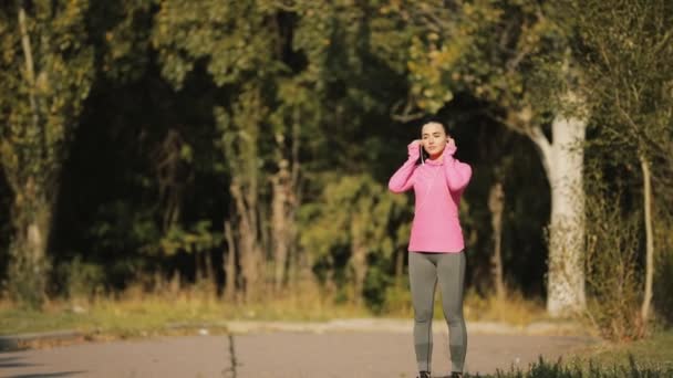 Bastante deportista en ropa deportiva rosa corriendo al aire libre, concepto de estilo de vida saludable. Movimiento lento
. - Metraje, vídeo