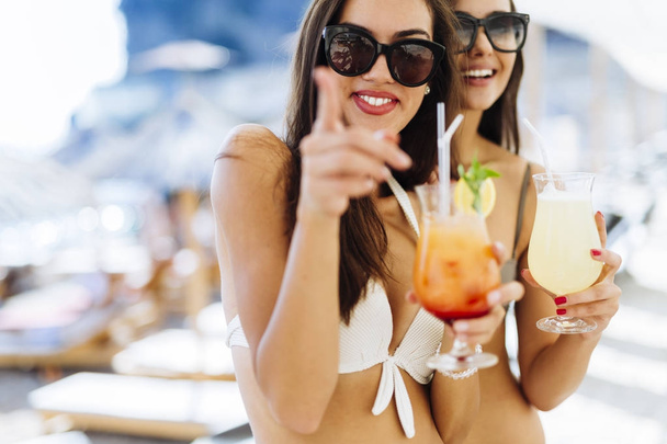 women on beach enjoying cocktails - Foto, afbeelding
