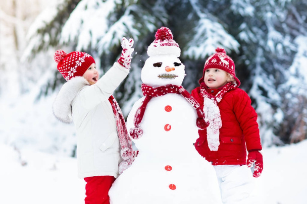 Дети строят снеговика. Дети в снегу. Зимнее веселье
. - Фото, изображение