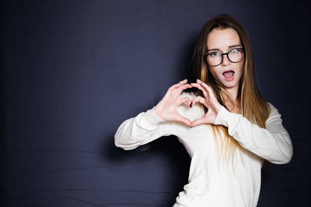 girl in glasses shows hands of heart from fingers - 写真・画像