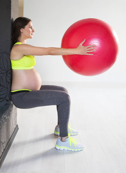 One young pregnant woman doing fitness exercises - Fotografie, Obrázek