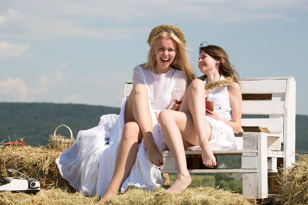Two girls sitting on bench on hay - Foto, Imagem
