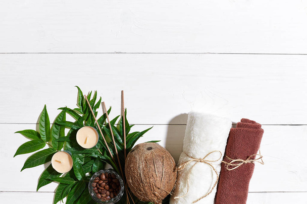 Σπα νεκρή φύση με πετσέτα, κεριά και πράσινα φύλλα σε μια λευκή ξύλινη επιφάνεια - Φωτογραφία, εικόνα